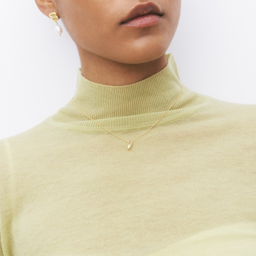 Brincos de prata 925 com banho de ouro 18K e pingente de pérola em modelo.