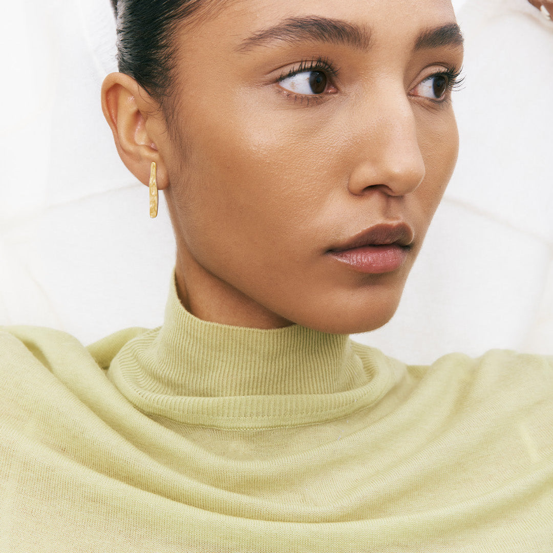 Brincos irregulares em pata 925 com banho de ouro 18k em modelo.