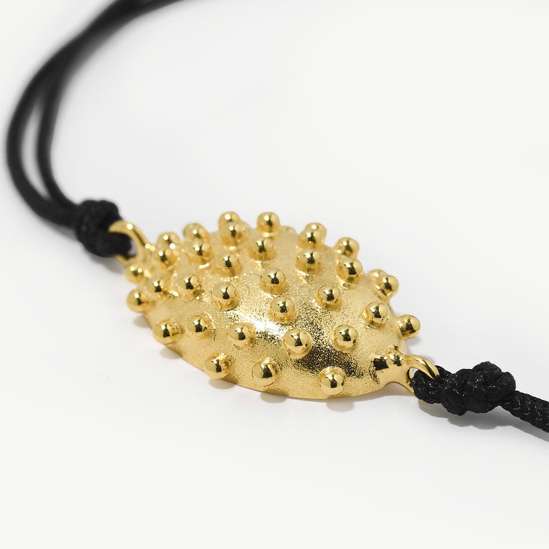 Pulseira ajustável de algodão com detalhe com relevos em prata 925 com banho de ouro 18k.