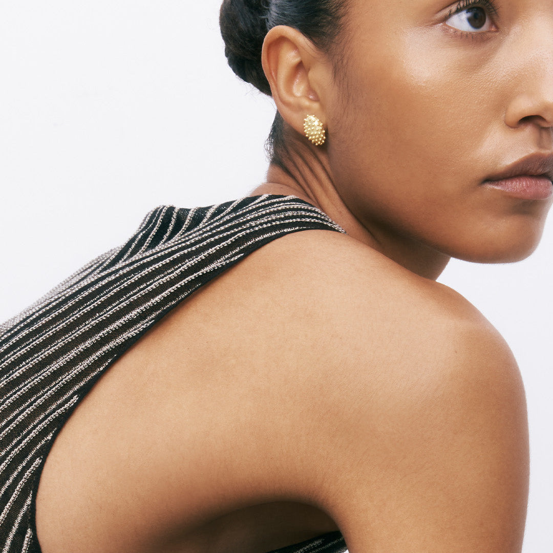 Brincos ovais com relevo em prata 925 com banho de ouro 18k em modelo.