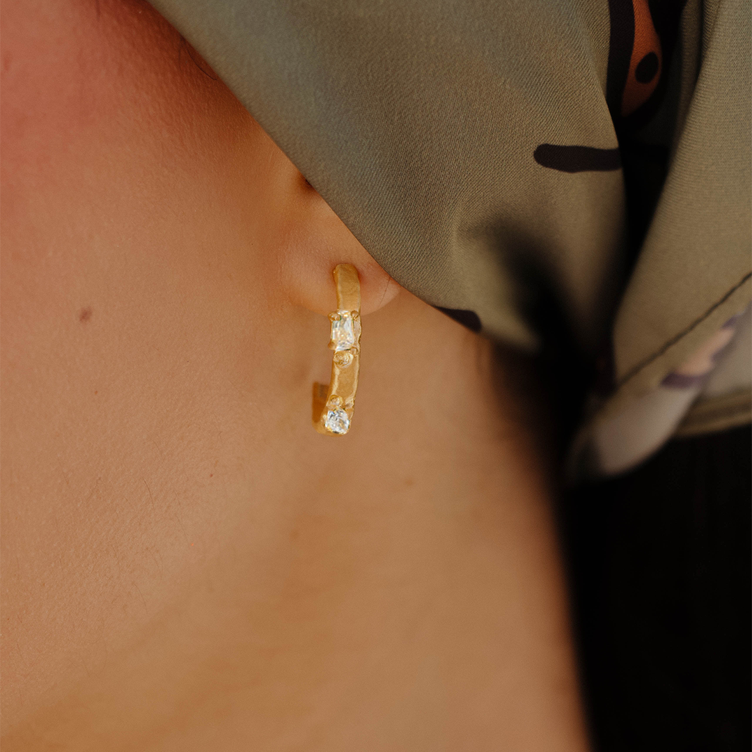 Argolas assimétricas em prata 925 com banho de ouro 18K e zircónias cúbicas em modelo.