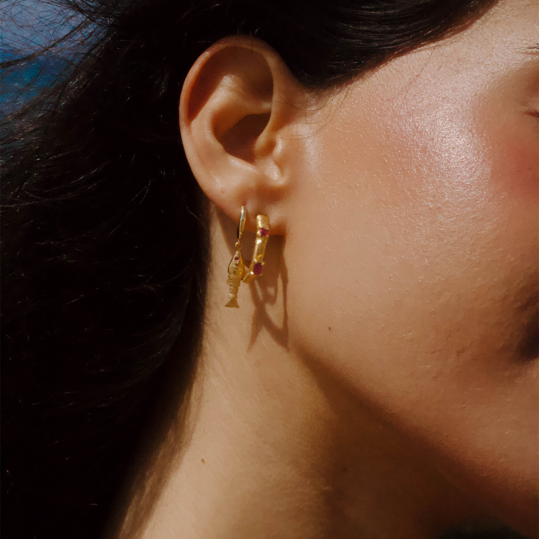 Argolas assimétricas em prata 925 com banho de ouro 18K e zircónias cúbicas rosa em modelo.