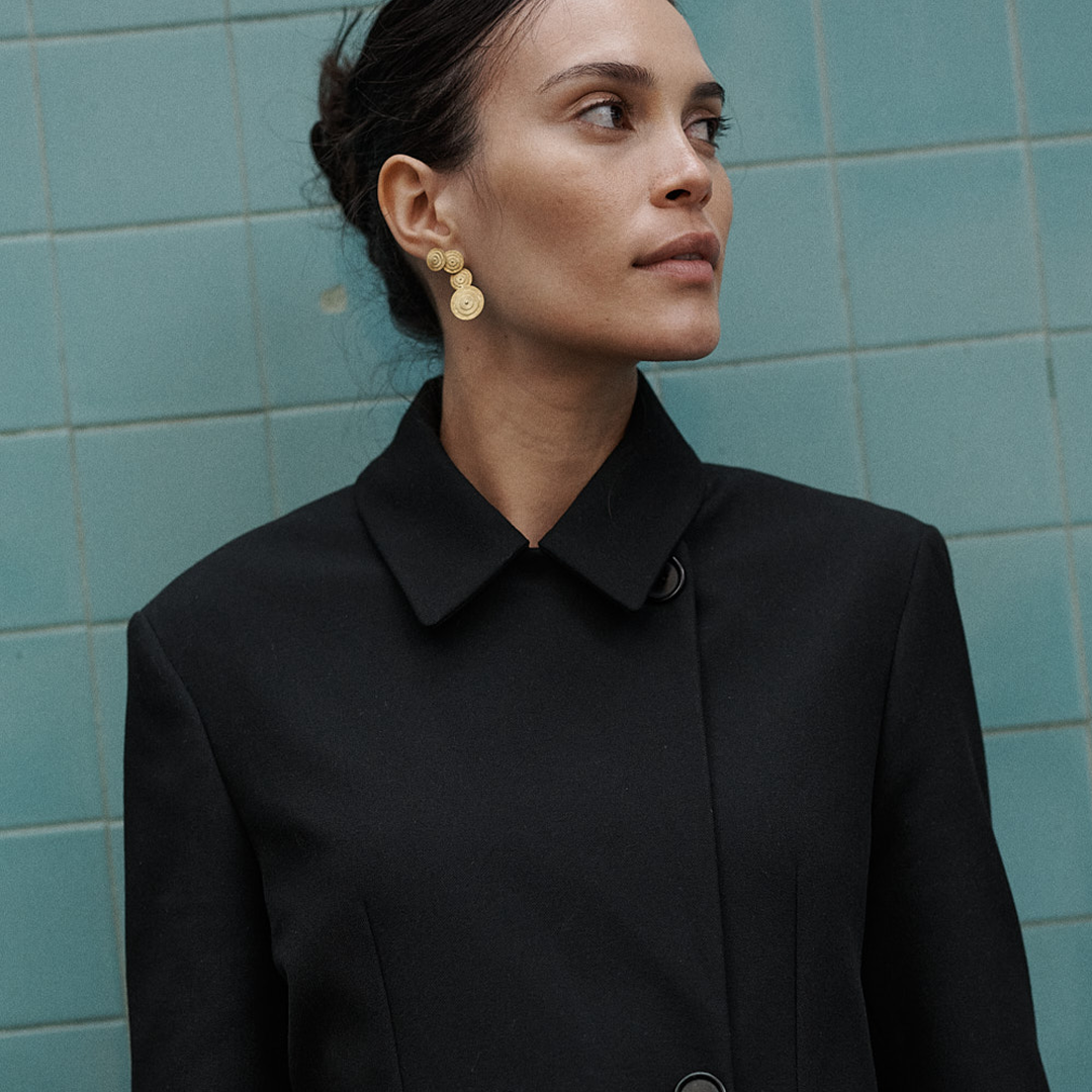 Brincos compridos articulados com detalhes redondos e relevo em prata 925 com banho de ouro 18K em modelo.