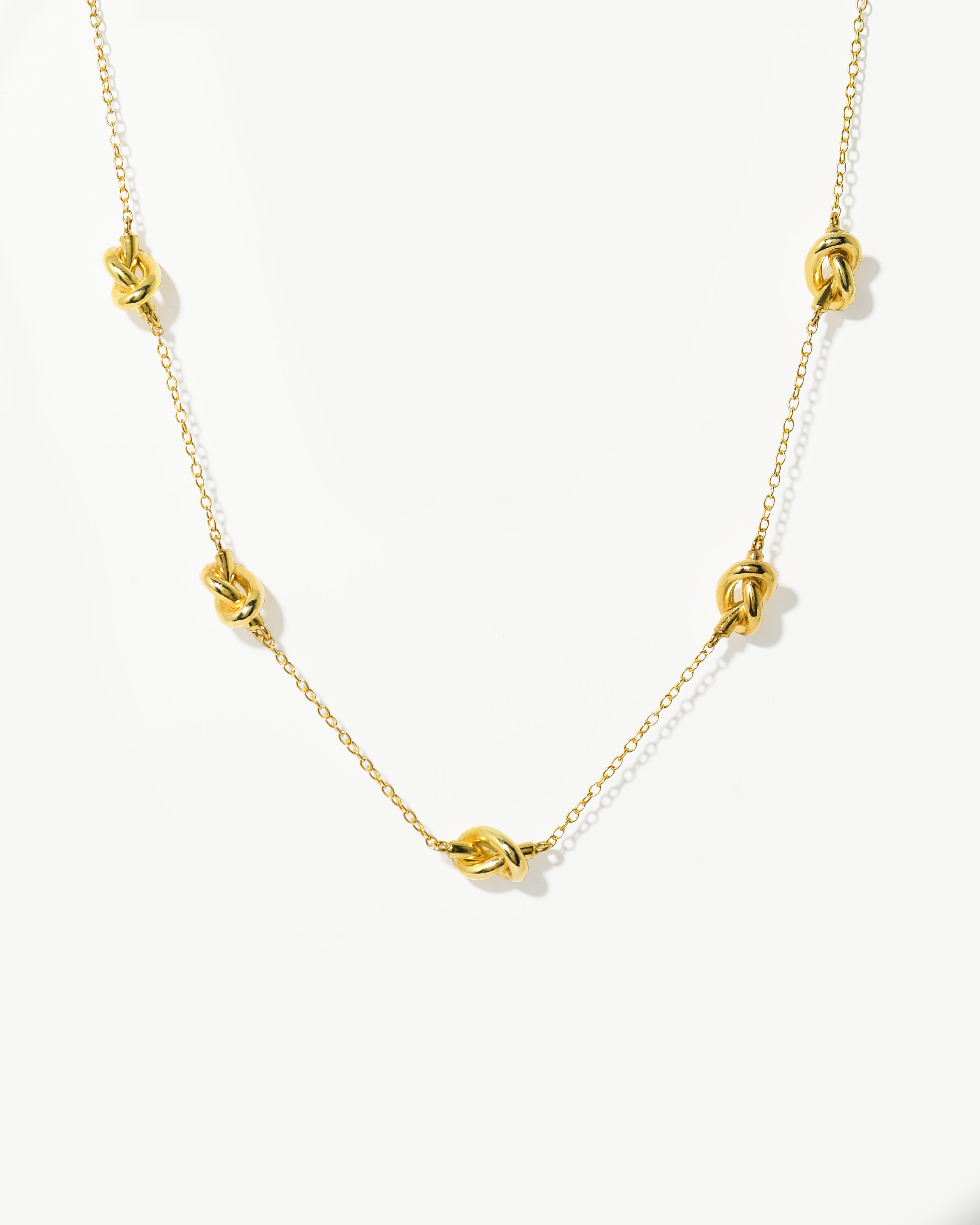 Colar de malha fina com nós em prata dourada.