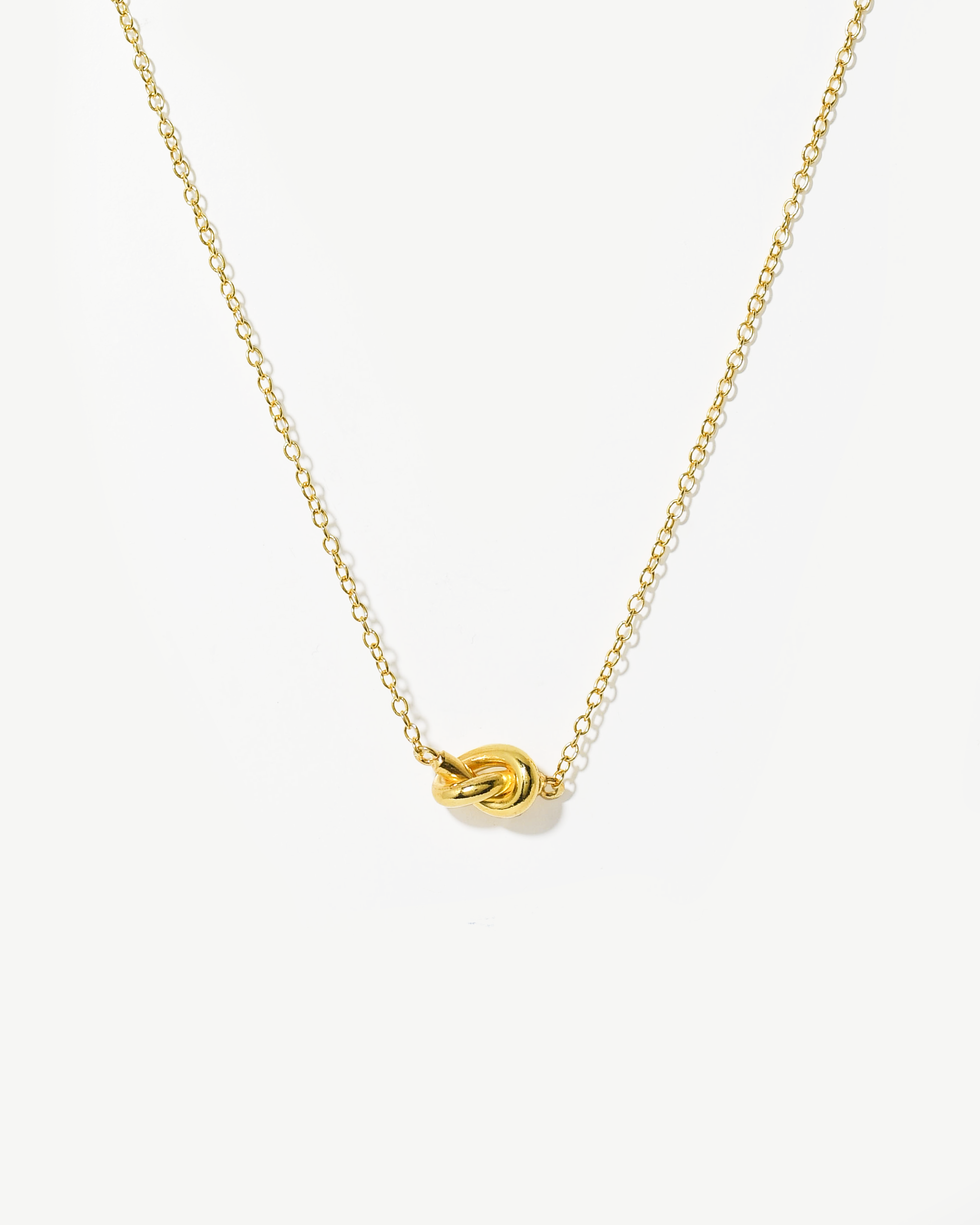 Colar com detalhe nó simples em prata dourada.