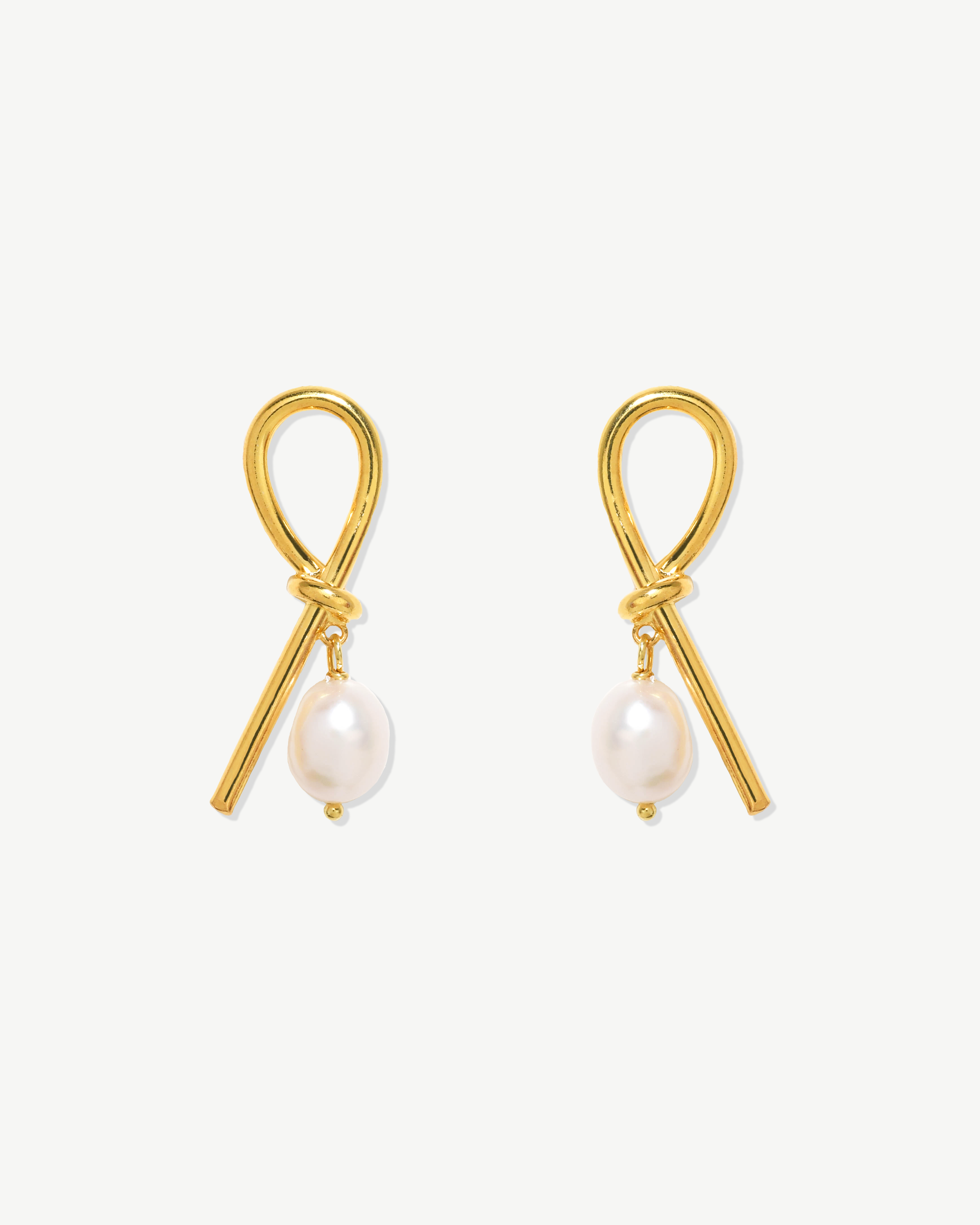 Brincos compridos em nó com pérola barroca. Prata dourada.