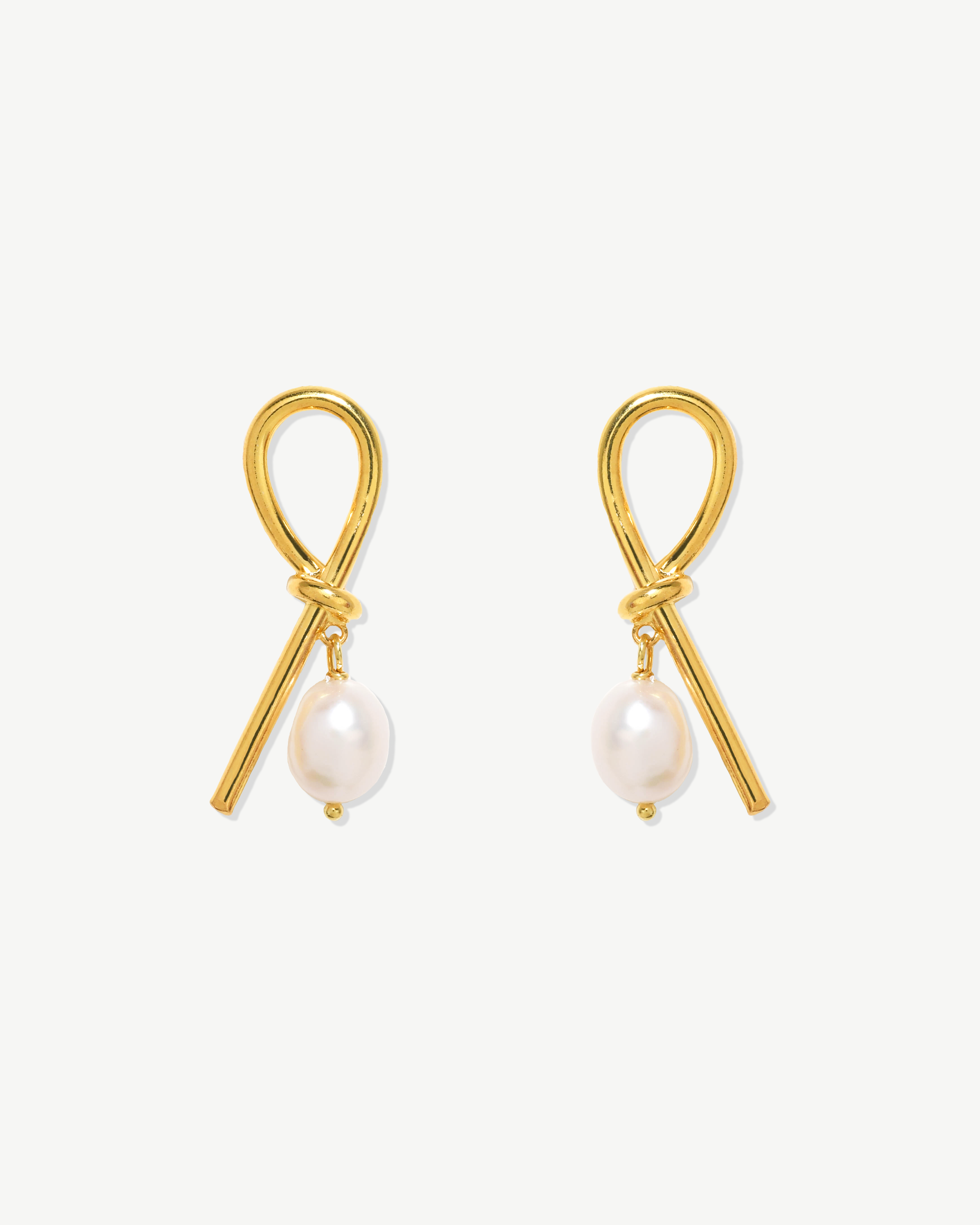 Brincos compridos em nó com pérola barroca. Prata dourada.