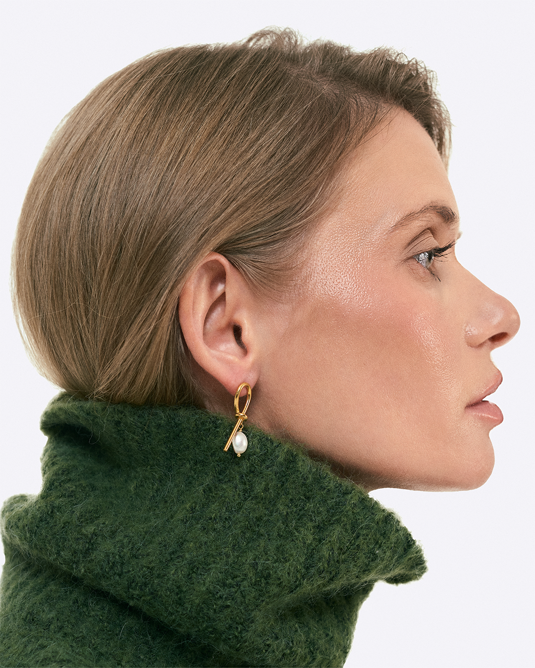 Modelo com brincos da coleçao knot em prata dourada.