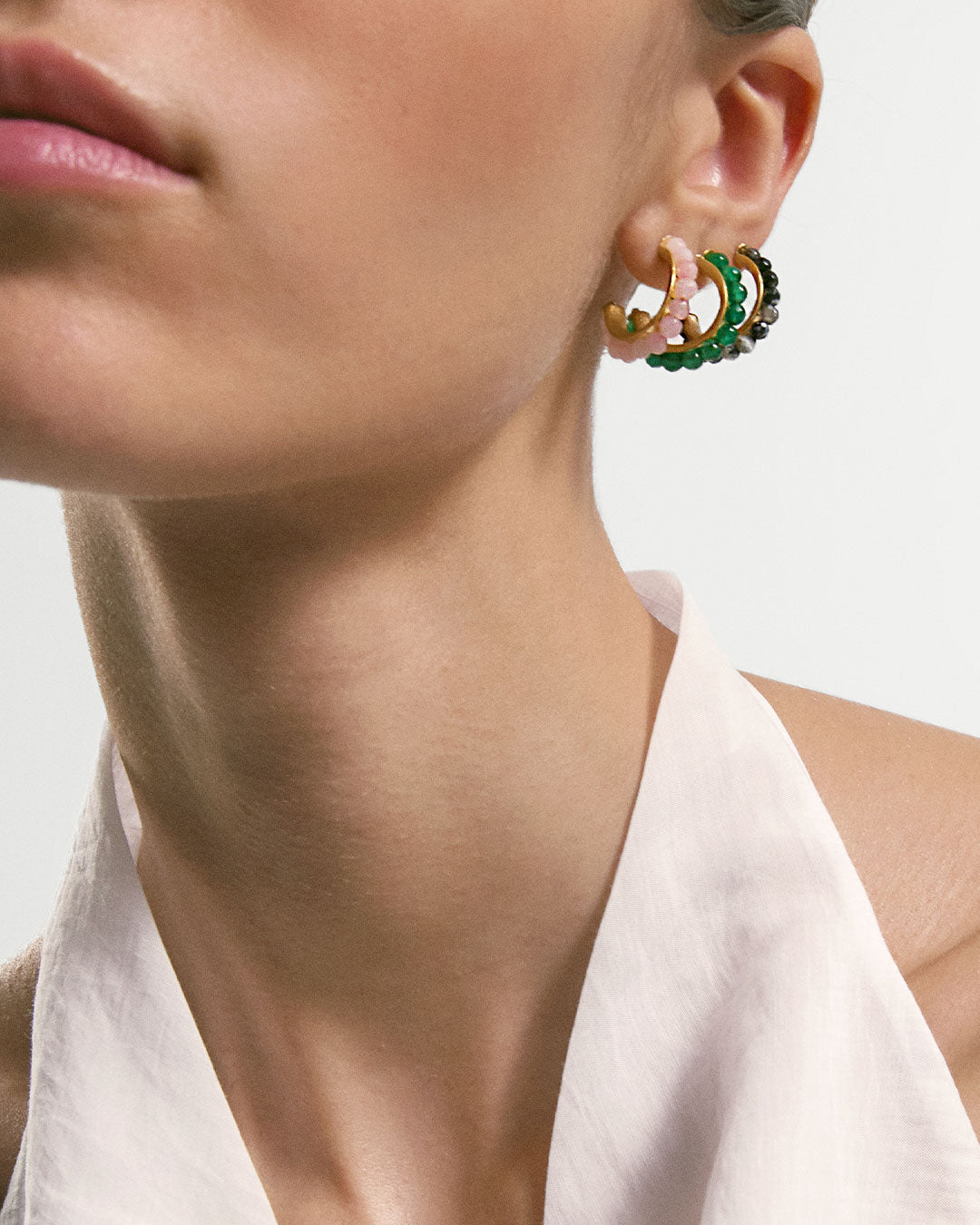 Argolas em prata 925 com banho de ouro 18K e pedras coloridas em modelo.