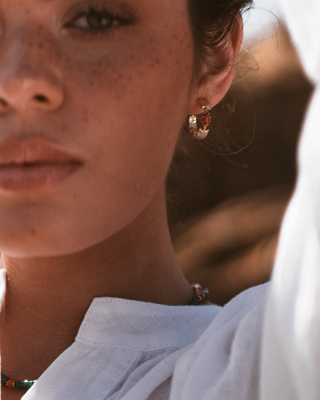 Argolas em prata 925 com banho de ouro 18K e pedras hidrotermais coloridas em modelo.