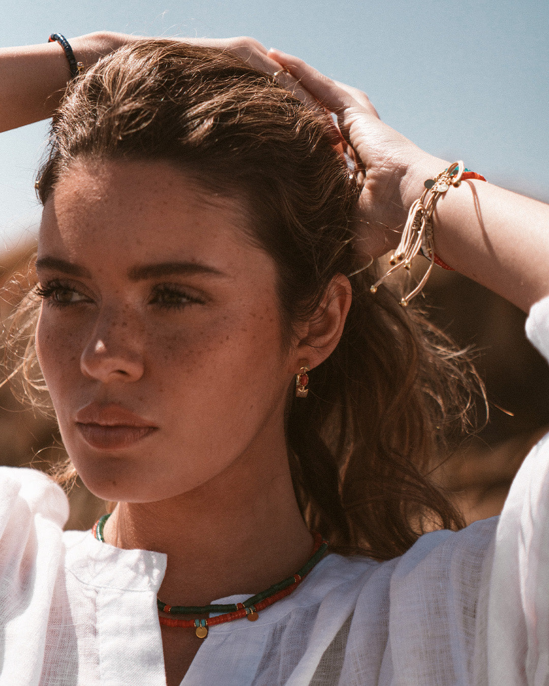 Argolas em prata 925 com banho de ouro 18K e pedras hidrotermais coloridas em modelo.